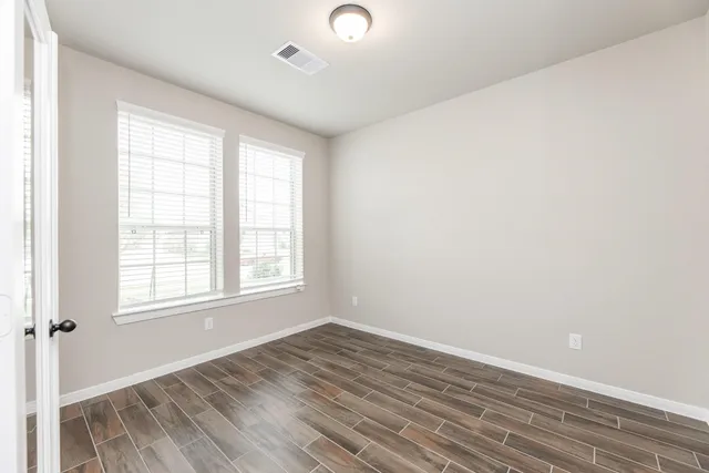 an empty room with wooden floor and windows