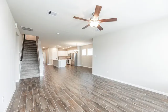 a view of a hallway with wooden floor and a ceiling fan