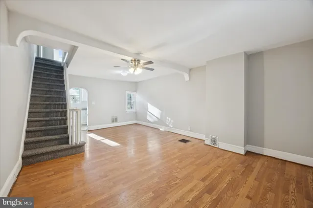 a view of empty room with wooden floor and fan