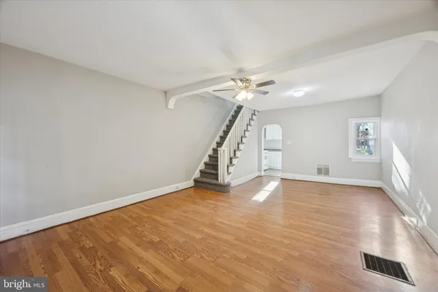 a view of an empty room with wooden floor and window