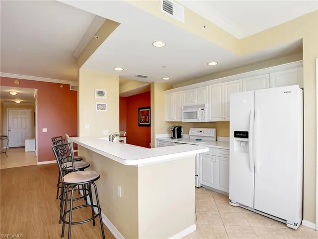 a kitchen with stainless steel appliances a white refrigerator a sink a stove a dining table and chairs