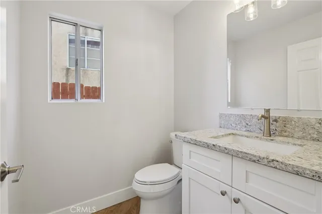 a bathroom with a granite countertop toilet sink and mirror