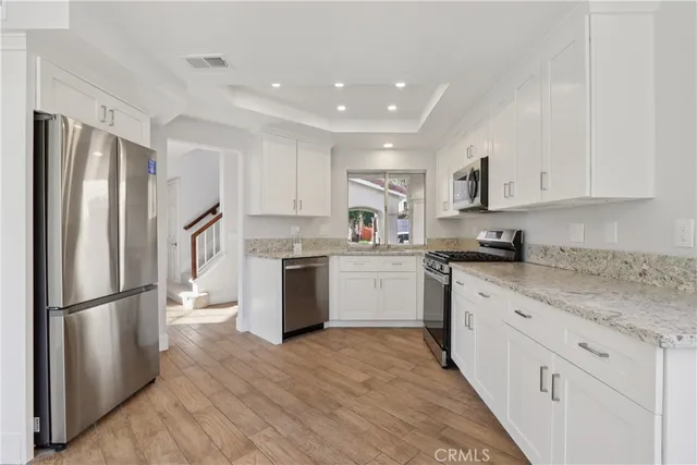 a kitchen with white cabinets stainless steel appliances and a refrigerator