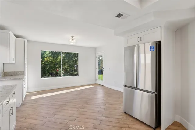 a view of kitchen with stainless steel appliances wooden floor and window