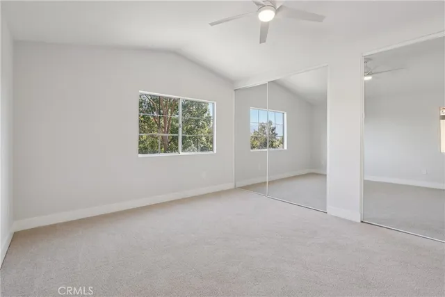 an empty room with windows and ceiling fan