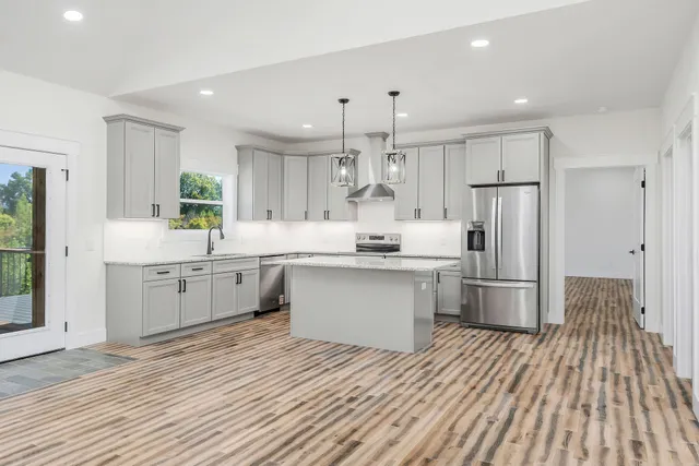 a kitchen with kitchen island white cabinets stainless steel appliances a sink and a center island