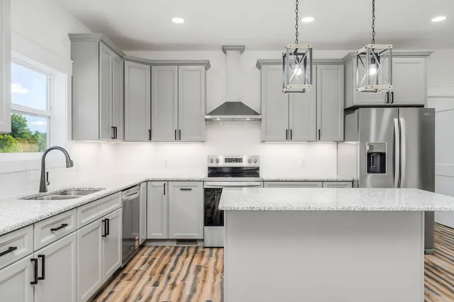 a kitchen with stainless steel appliances granite countertop a sink a stove and refrigerator