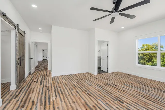 a view of a big room with wooden floor a ceiling fan and windows