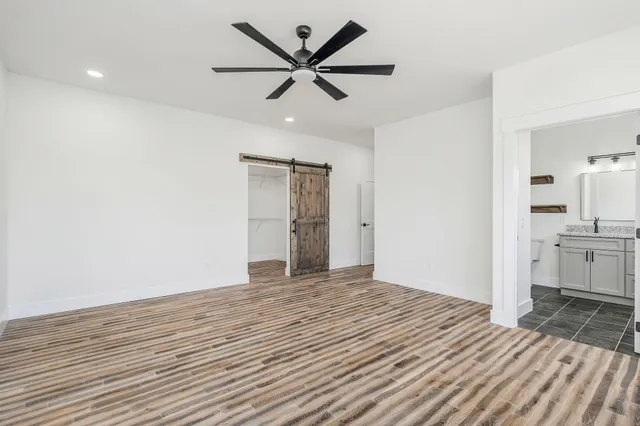 a view of a livingroom with a chandelier fan and wooden floor