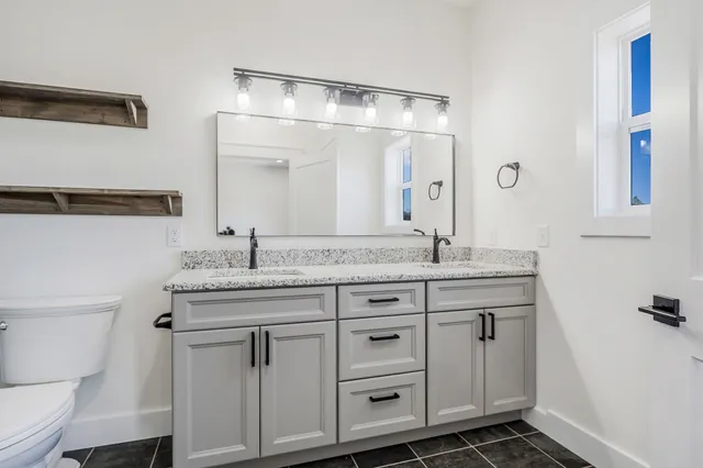 a bathroom with a granite countertop sink a toilet and a mirror