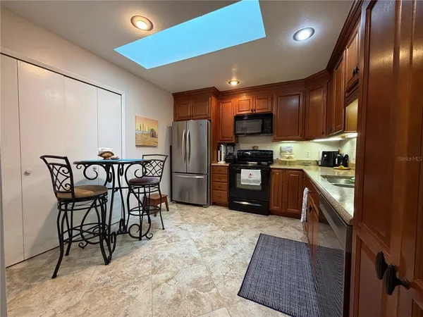 a kitchen with stainless steel appliances a refrigerator a stove a sink dishwasher with a dining table and chair