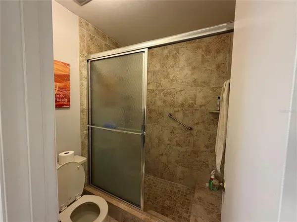 a bathroom with a granite countertop shower and a toilet