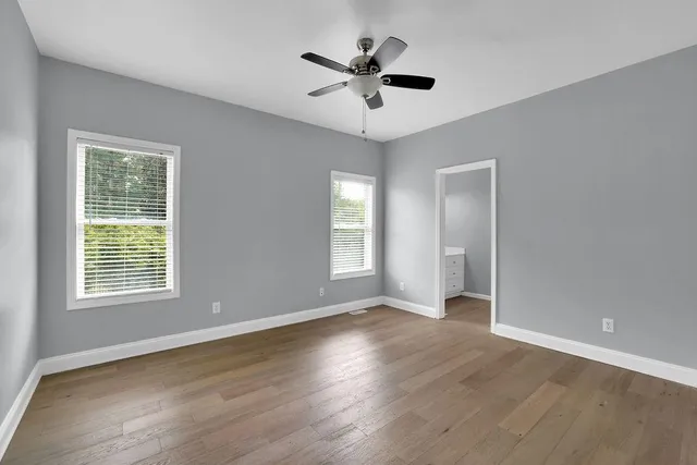 an empty room with wooden floor and windows