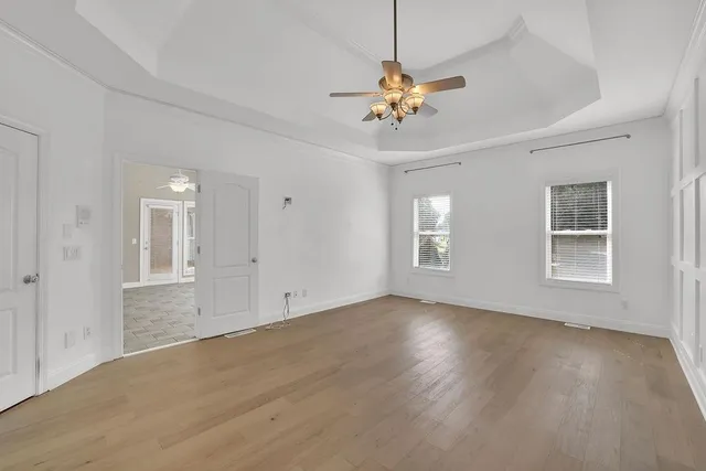 a view of an empty room with a window and wooden floor