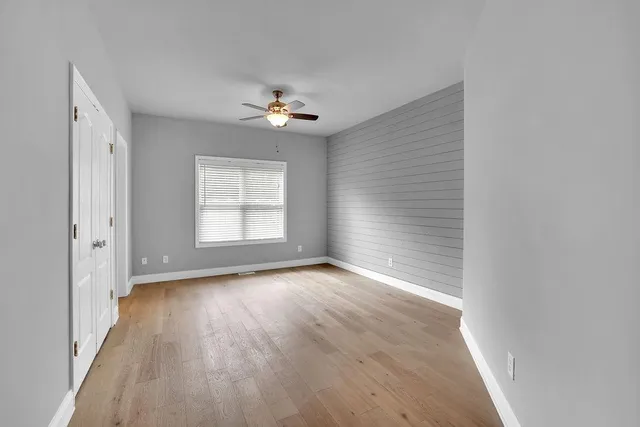 a view of empty room with wooden floor and fan