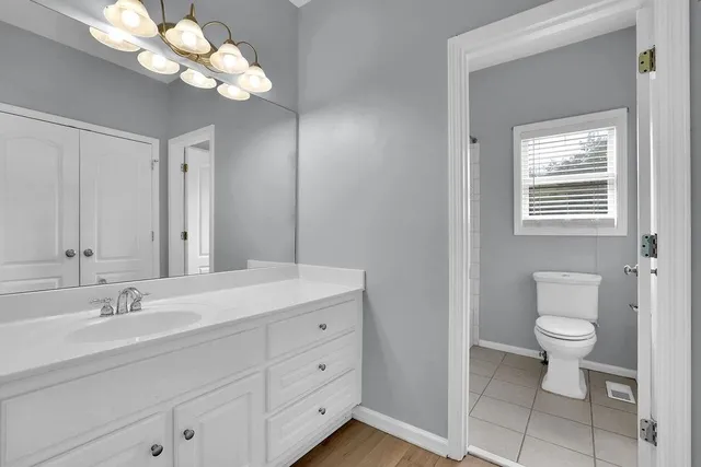 a bathroom with a toilet a sink a mirror and a window