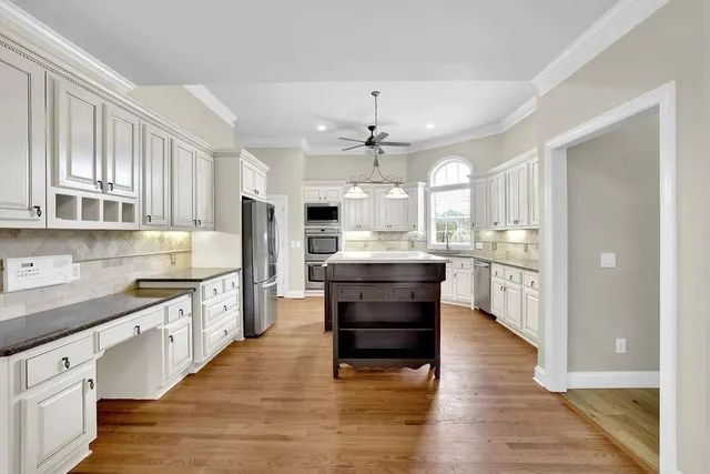 a kitchen with stainless steel appliances kitchen island granite countertop a refrigerator a stove and a sink with cabinets