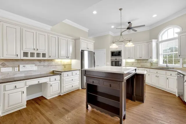 a kitchen with stainless steel appliances granite countertop wooden cabinets granite counter tops and a hard wood floors
