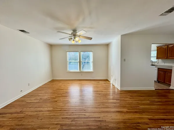 a view of an empty room with a window and wooden floor