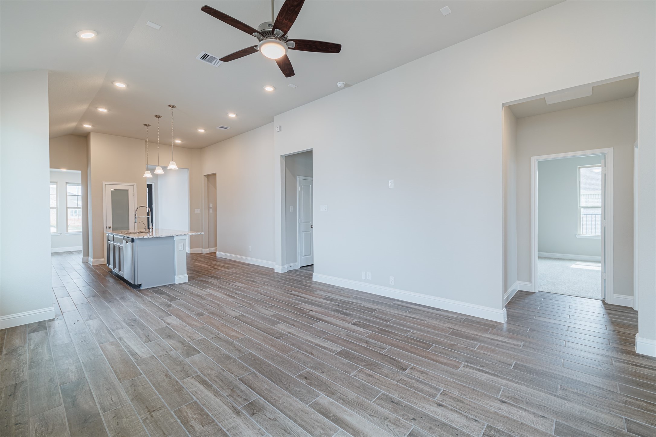12611 White Pelican Court Cypress, TX 77433 - Photo 11 of 24 a view of a big room with wooden floor a ceiling fan and kitchen view