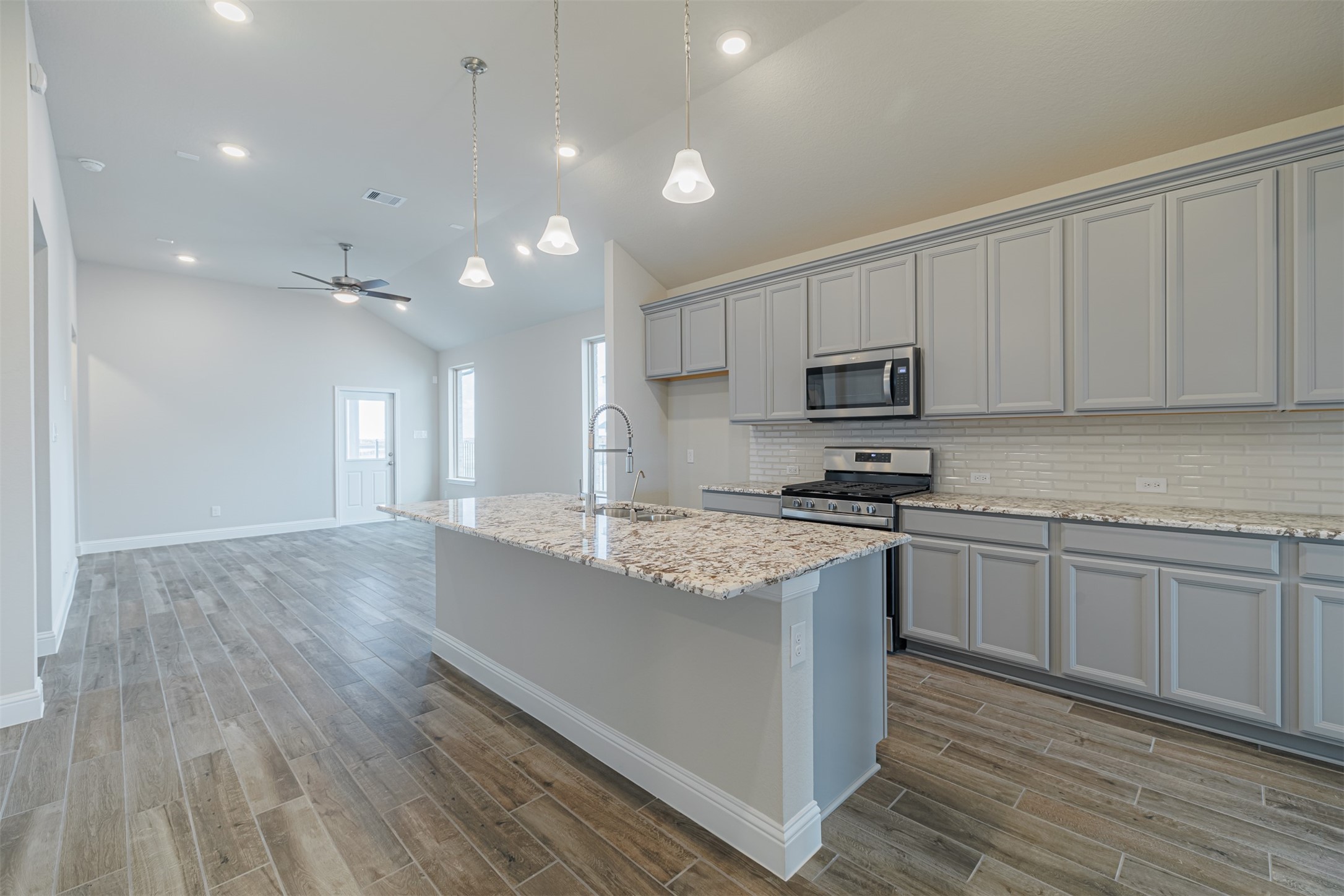 12611 White Pelican Court Cypress, TX 77433 - Photo 8 of 24 a kitchen with stainless steel appliances granite countertop a stove a sink and a microwave