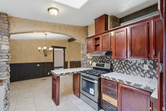 2875 North Hill Field Road, Unit 111 Layton, UT 84041 - Photo 2 of 30 Kitchen featuring tile countertops, wainscoting, stainless steel range with gas stovetop, open shelves, and arched walkways