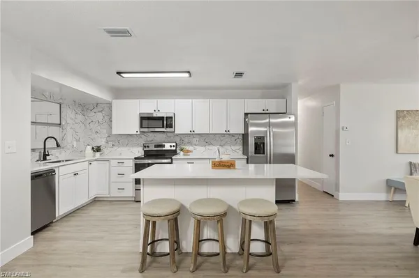 a kitchen with stainless steel appliances granite countertop a stove a sink dishwasher and a refrigerator with wooden floor