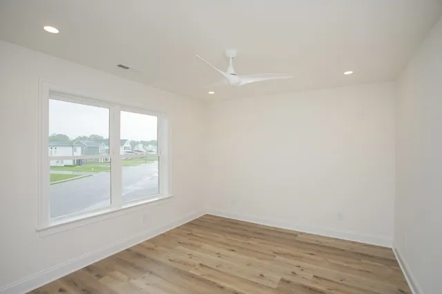 an empty room with wooden floor and windows