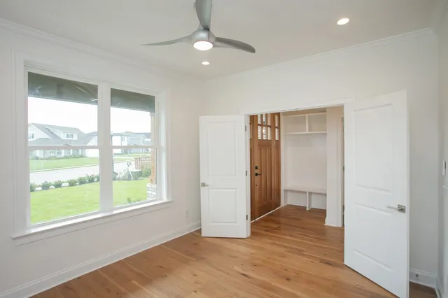 a view of an empty room with wooden floor and a window