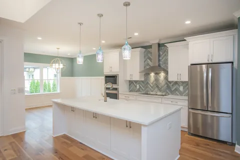 a view of a kitchen with a refrigerator a sink and wooden floor