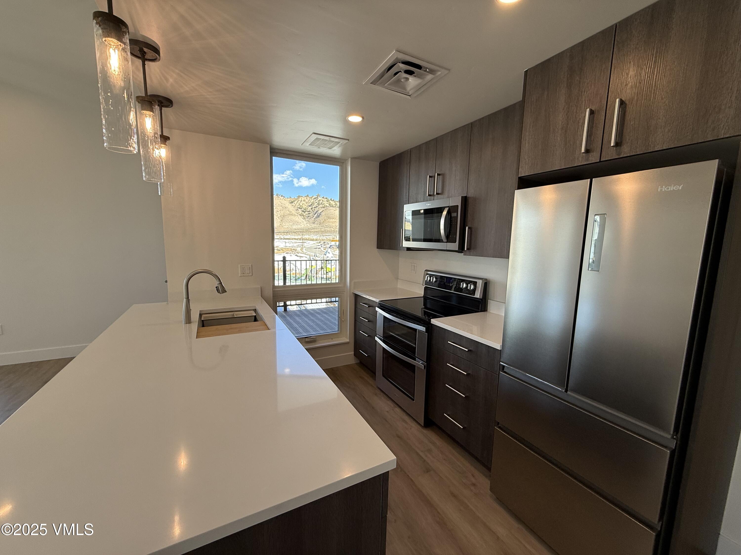 91 Mount Hope Circle, Unit G301 Eagle, CO 81631 - Photo 4 of 13 a kitchen with stainless steel appliances a refrigerator sink and wooden cabinets