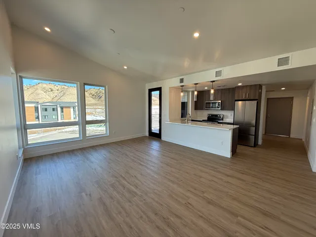 a view of a kitchen center island wooden floor and stainless steel appliances