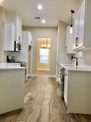 a room with a sink a refrigerator and cabinets