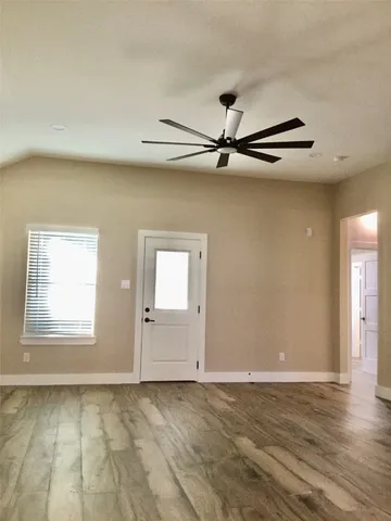 an empty room with wooden floor cabinet and windows