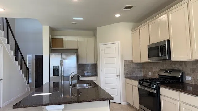 a kitchen with stainless steel appliances granite countertop a sink a stove and a refrigerator