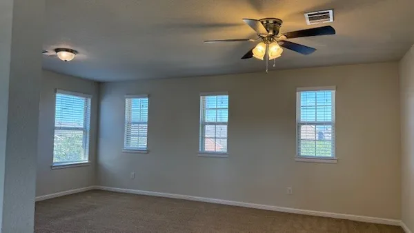 a view of an empty room with a window and chandelier fan