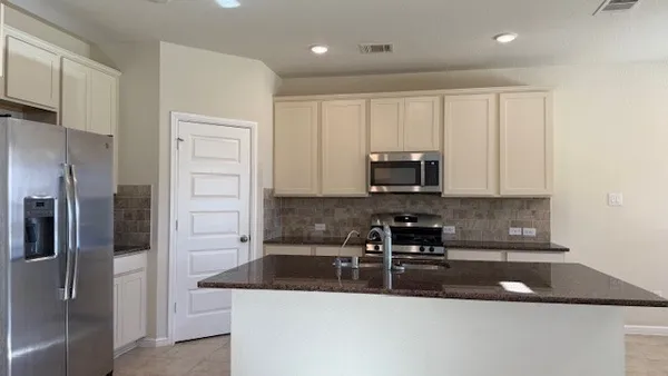 a kitchen with stainless steel appliances granite countertop a sink a stove and a refrigerator