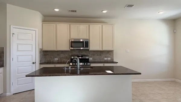 a kitchen with stainless steel appliances a sink a stove a microwave a refrigerator and cabinets