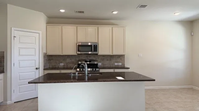 a kitchen with stainless steel appliances a sink a stove a microwave a refrigerator and cabinets