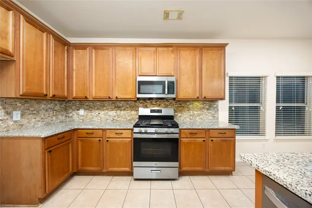 a kitchen with stainless steel appliances granite countertop a stove a sink and a microwave