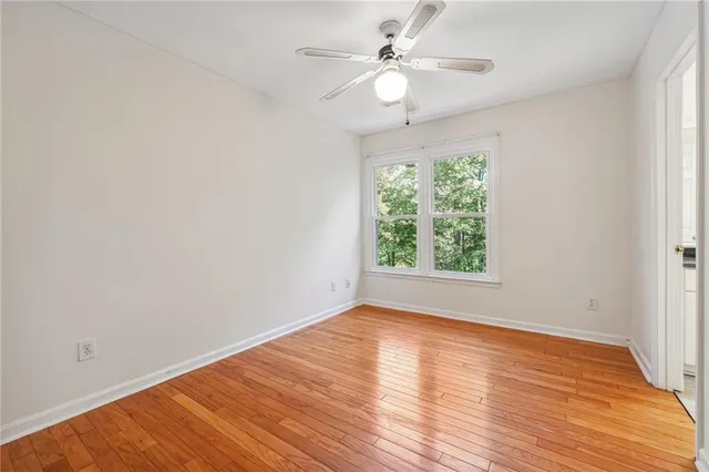 an empty room with wooden floor fan and windows