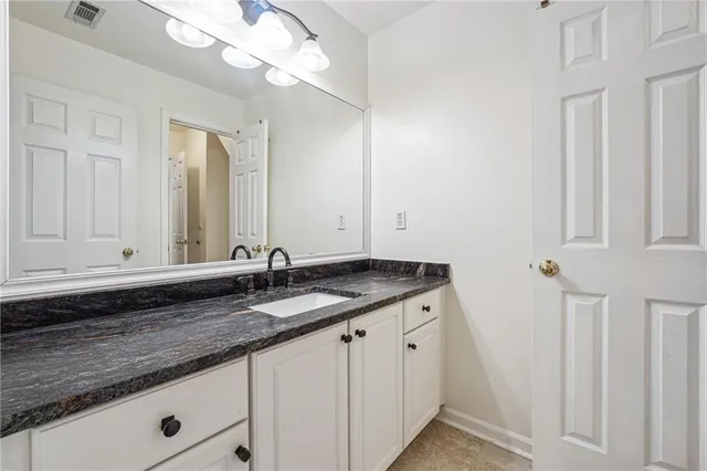 a bathroom with a granite countertop sink and a mirror