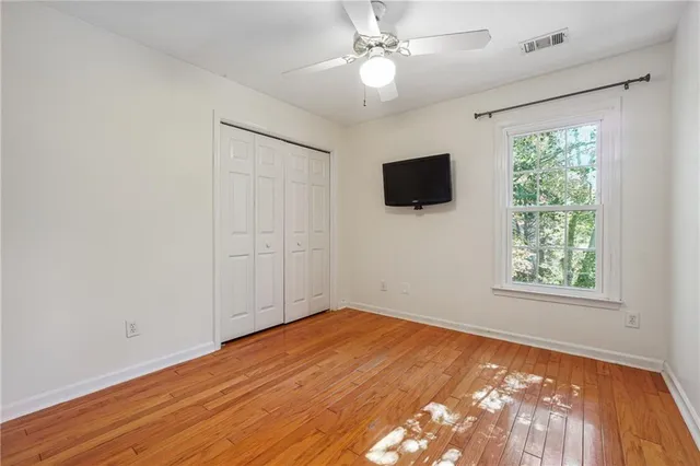 an empty room with wooden floor fan and windows