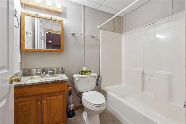 a bathroom with a granite countertop toilet sink and mirror