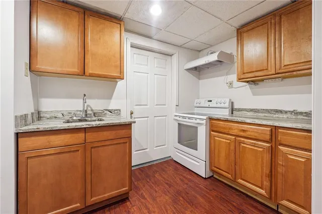 a kitchen with granite countertop cabinets stainless steel appliances a sink and wooden floor