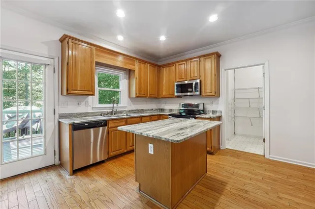 a kitchen with stainless steel appliances granite countertop wooden cabinets a stove a sink and a large window