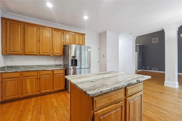a kitchen with stainless steel appliances granite countertop wooden cabinets and wooden floor