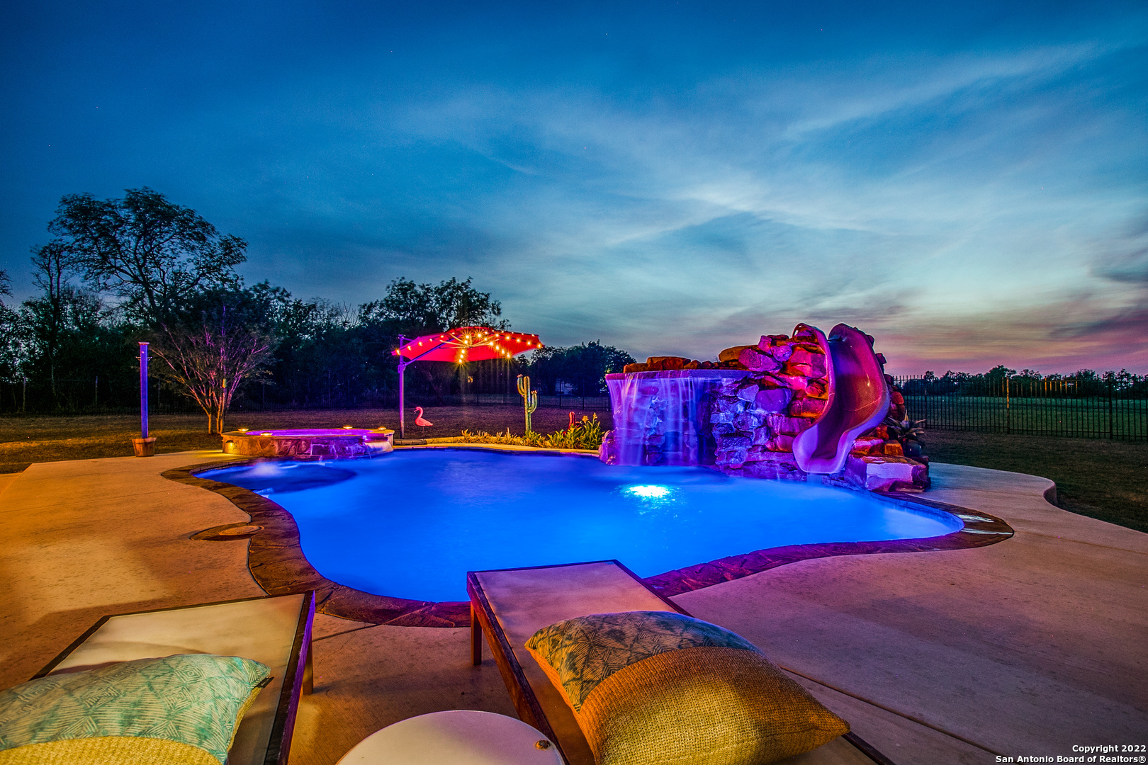 a view of a pool a fire pit and outdoor kitchen