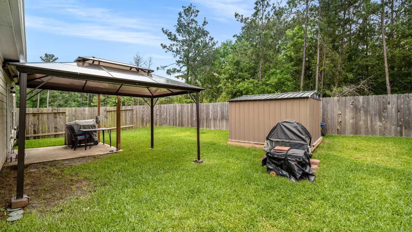 14449 Sunny Bend Way Conroe, TX 77303 - Photo 29 of 34 a view of backyard with small cabin and wooden fence