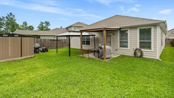 a view of a backyard with wooden fence and large trees